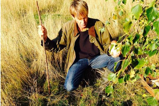Martin Denny of Martin Denny Wild Foods crouching in long autumn grass