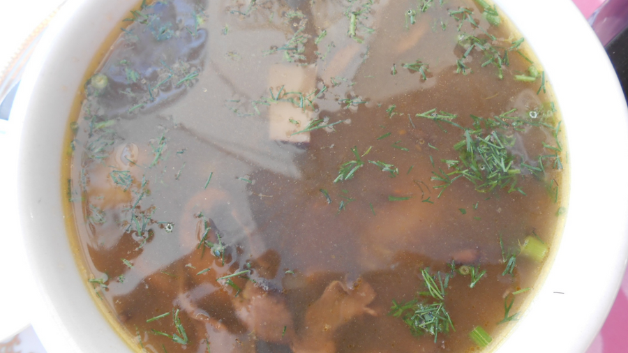 Bowl of clear shiitake mushroom broth with fresh herbs